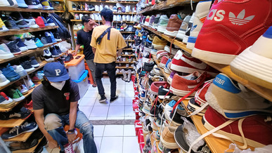 Pengunjung mencoba sepatu bekas layak pakai (thrifting) di Pasar Loak Gedebage, Bandung.