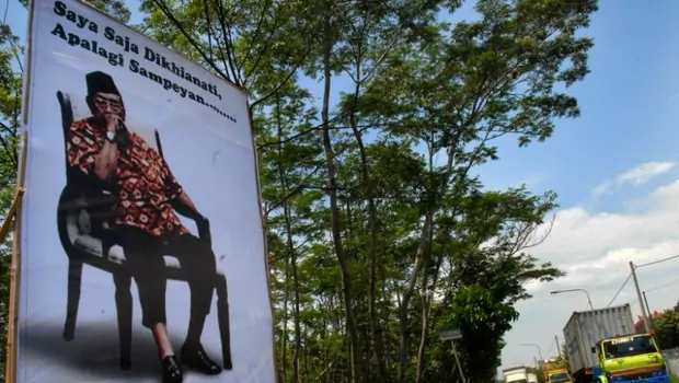 Sejumlah kendaraan melintas di samping baliho bergambar Gus Dur yang bertuliskan Saya Saja Dikhianati Apalagi Sampeyan di Jalan Raya Warung Dowo, Pasuruan, Jatim.