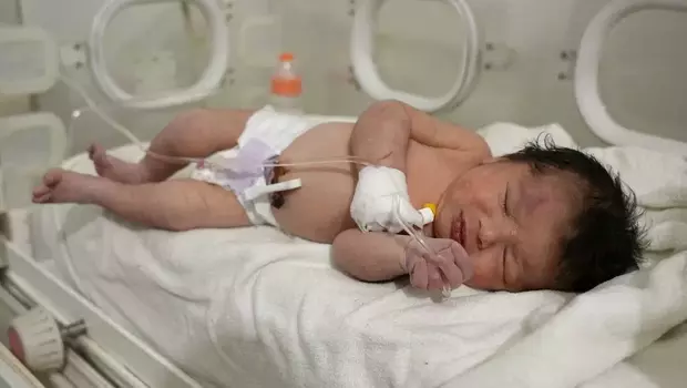 Seorang bayi baru lahir yang ditemukan masih terikat tali pusar ke ibunya dan ditarik hidup-hidup dari puing-puing sebuah rumah di utara setelah gempa mematikan, menerima perawatan medis di sebuah klinik di Afrin, pada 7 Februari 2023.