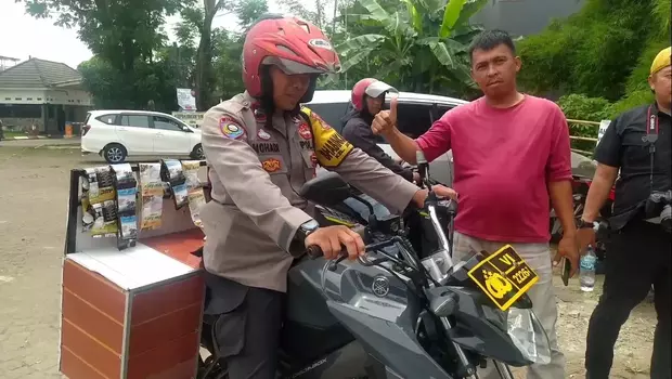 Aipda Mohadi, anggota Kepolisian Polres Metro Depok yang bertugas sebagai Bhabinkamtibmas di Polsek Sukmajaya, Depok, Jawa Barat menjajakan kopi panas sambil berkeliling dengan motor dinas yang sudah dimodifikasi.