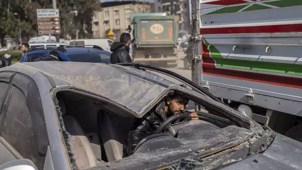 Seorang warga di Antakya, tenggara Turki, pada Minggu, 12 Februari 2023 mengendarai mobil yang rusak akibat gempa Turki berkekuatan M 7,8.