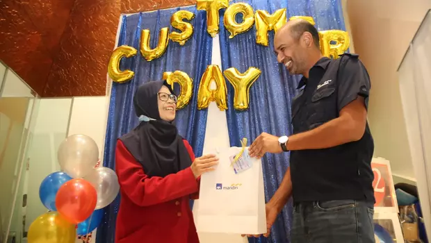 Direktur AXA Mandiri Aayush Poddar (kanan) memberikan bingkisan setelah menyapa dan melayani nasabah pada Hari Pelanggan Nasional 2023 di Jakarta, Senin 4 September 2023.