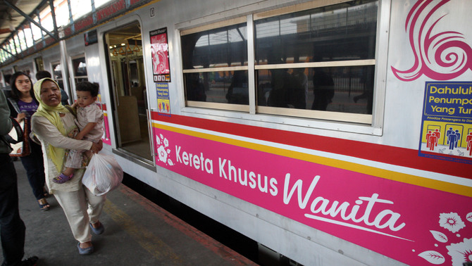 Penumpang berjalan melintasi rangkaian KRL khusus perempuan yang berhenti di Stasiun Pasar, Senen, Jakarta. FOTO: Yudhi Sukma Wijaya / JAKARTA GLOBE
