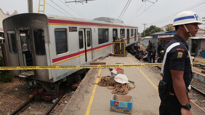 Seorang petugas mengamankan lokasi gerbong KRL Commuter Line yang anjlok di Stasiun Cilebut, Bogor, Jawa Barat. FOTO: Safir Makki/ JAKARTA GLOBE