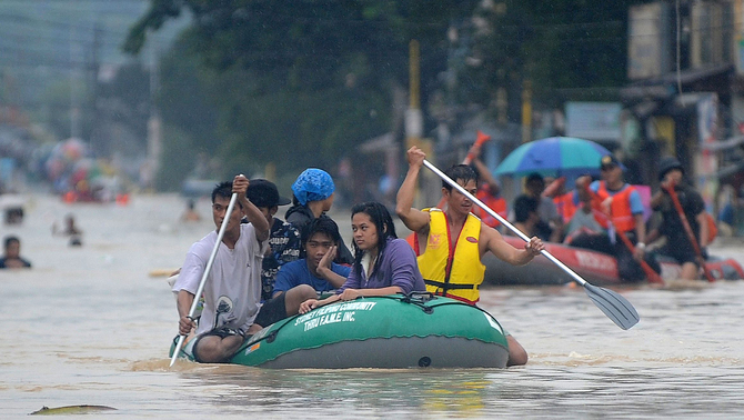 Tim penyelamat mengevakuasi warga dengan menggunakan perahu karet saat banjir melanda kawasan Marikina, Manila, Filipina. FOTO: AFP PHOTO / TED ALJIBE