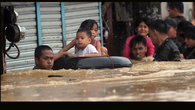 Warga melintasi kawasan yang dilanda banjir dengan berpegangan tali saat  banjir melawan kawasan Marikina, Manila, Filipina. FOTO: AFP PHOTO / TED ALJIBE