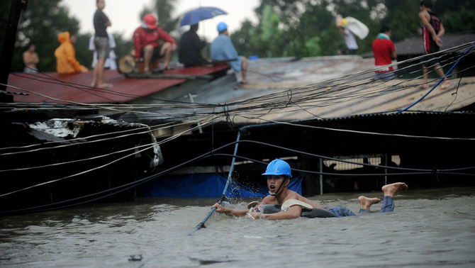Seorang warga dengan menggunakan ban melintasi banjir yang melanda kawasan Manila, Filipina. FOTO:   AFP PHOTO/NOEL CELIS