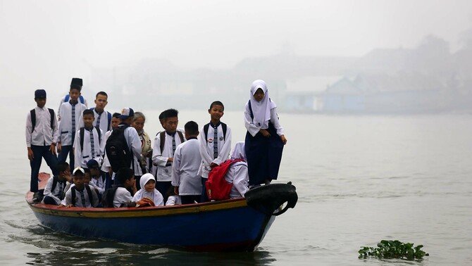 Sejumlah warga dan anak sekolah naik perahu sebagai alat transportasi menuju ke sekolah di tepian sungai Musi, Palembang, Sumatra Selatan, 30 Oktober 2015.