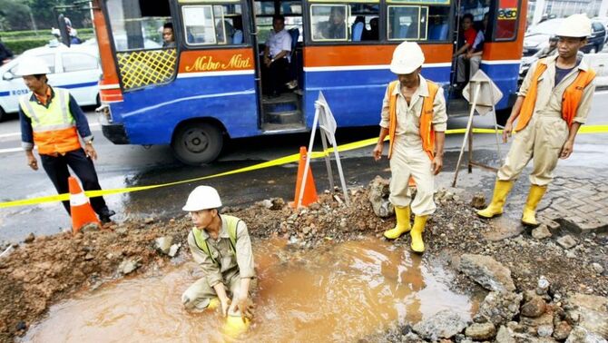 Pekerja melpas lelah sebelum melanjutkan pekerjaan pipa air milik PT PAM Lyonnaise Jaya (Palyja) yang bocor di Semanggi, Gatot Subroto, Jakarta Pusat, Senin (8/4). Kebocoran pipa tersebut diduga akibat tekanan beban dari luar sehingga pipa 200 mm tersebut bocor dan air mengenangi badan jalan.
