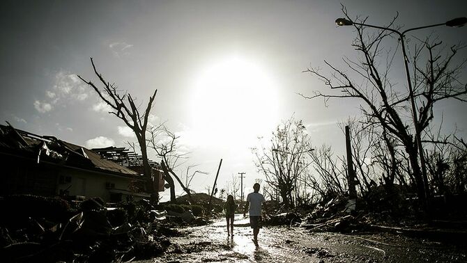 Dua warga berjalan di tengah puing bangunan dan pepohonan yang tumbang seminggu setelah topan Haiyan menghantam wilayah tersebut.