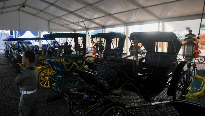 Petugas Satpol PP menjaga kereta kencana yang disiapkan untuk kirab, dalam rangka Pagelaran Agung Keraton se-Dunia di kawasan Monumen Nasional, Jakarta, Kamis (5/12). Pagelaran diikuti sepuluh perwakilan kerajaan dari luar negeri dan lebih dari seratus kerajaan di Nusantara. Pagelaran diisi beragam acara seni, budaya, kuliner, dan ditutup kirab budaya pada tanggal 8 Desember 2013. SP/Joanito De Saojoao.