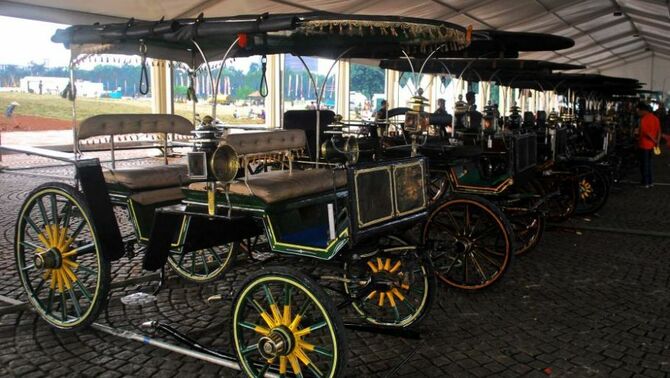 Pengunjung mengamati kereta kencana yang disiapkan untuk kirab, dalam rangka Pagelaran Agung Keraton se-Dunia di kawasan Monumen Nasional, Jakarta, Kamis (5/12). Pagelaran diikuti sepuluh perwakilan kerajaan dari luar negeri dan lebih dari seratus kerajaan di Nusantara. Pagelaran diisi beragam acara seni, budaya, kuliner, dan ditutup kirab budaya pada tanggal 8 Desember 2013. SP/Joanito De Saojoao.