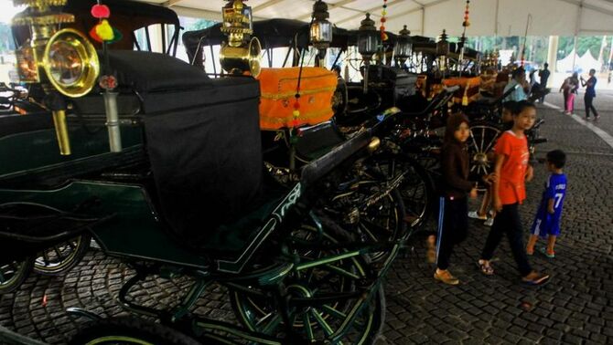 Pengunjung mengamati kereta kencana yang disiapkan untuk kirab, dalam rangka Pagelaran Agung Keraton se-Dunia di kawasan Monumen Nasional, Jakarta, Kamis (5/12). Pagelaran diikuti sepuluh perwakilan kerajaan dari luar negeri dan lebih dari seratus kerajaan di Nusantara. Pagelaran diisi beragam acara seni, budaya, kuliner, dan ditutup kirab budaya pada tanggal 8 Desember 2013. SP/Joanito De Saojoao.