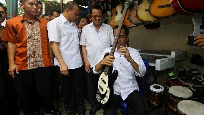 Gubernur DKI Jakarta yang juga Presiden terpilih Joko Widodo mencoba gitar bass   saat mengunjungi Pasar Klithikan Notoharjo, Semanggi, Kota Surakarta, Jawa Tengah, Sabtu (26/7). SP/Joanito De Saojoao.