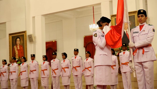 Anggota Pasukan Pengibar Bendera (Paskibraka) tahun 2015 asal Lampung Della Elvira (kiri) mencium bendera Merah Putih saat pengukuhan yang dipimpin Presiden Joko Widodo di Istana Negara, Jakarta, Sabtu (15/8).