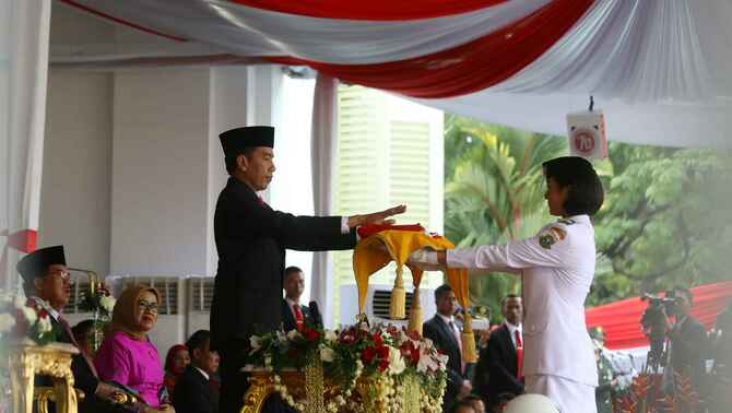 Presiden RI Joko Widodo selaku pemimpin upacara menyerahkan bendera pusaka kepada anggota paskibraka, Maria Felicia Gunawan asal Banten, dalam upacara peringatan detik-detik proklamasi dalam rangka HUT RI ke -70 di Istana Merdeka, Jakarta, Senin (17/8).