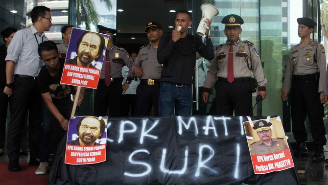 Massa yang menamakann diri Jaringan Masyarakat Anti Korupsi (Jamak) membawa keranda mayat, poster Surya Paloh dan Jaksa Agung HM Prasetyo meminta Komisi Pemberantasan Korupsi (KPK) untuk segera memangil mereka berdua terkait kasus 'pengamanan' perkara dana Bantuan Sosial Pemprov Sumut, di depan gedung KPK, Jalan HR Rasuna Said, Jakarta Selatan, Senin (28/12).
