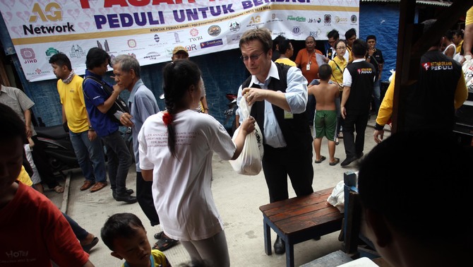 Rudolf Herrmann General Manager Discovery Hotel dan Convention Ancol memberikan secara cuma-cuma paket sembako kepada warga yang tidak mampu di kawasan Pademangan, Jakarta Utara, Rabu (30/12/2015).