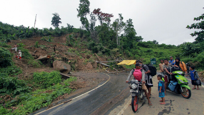 Sejumlah warga pengguna kendaraan sepeda motor berputar balik arah akibat jalan yang tertutup longsor sepanjang 50 meter dengan ketinggian 15 meter di Desa Kikia, Kabupaten Gorontalo Utara, Gorontalo, 27 Februari 2017. Jalan Lintas Sulawesi yang menghubungkan Provinsi Gorontalo dan Buol, Sulawesi Tengah, lumpuh akibat longsor yang terjadi di 83 titik.