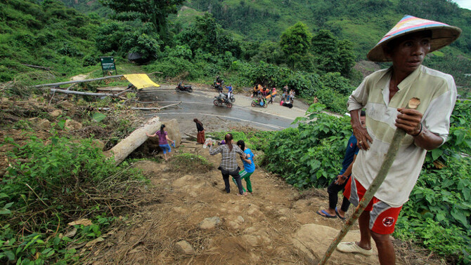 Warga berjalan menghindari longsor sepanjang 50 meter dengan ketinggian 15 meter yang menutup akses jalan, di Desa Kikia, Kabupaten Gorontalo Utara, Gorontalo, 27 Februari 2017.