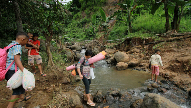 Sejumlah warga dari arah Desa Kasia berjalan menyeberangi sungai untuk menuju Desa Kikia di Kabupaten Gorontalo Utara, Gorontalo, 27 Februari 2017.