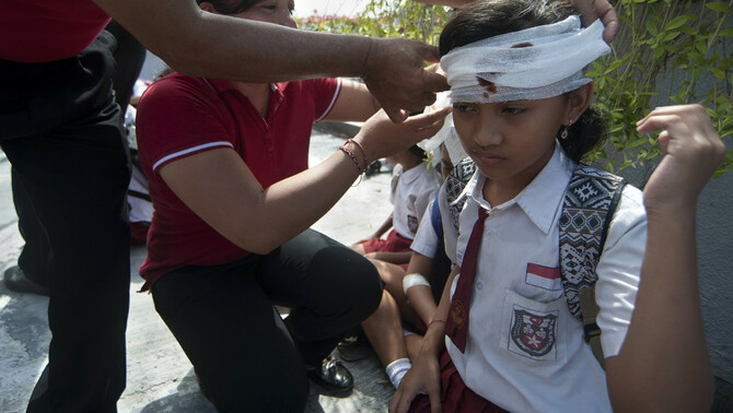 Petugas medis menangani siswa yang terluka saat simulasi gempa bumi dan tsunami di Tanjung Benoa, Badung, Bali, 15 Agustus 2017.