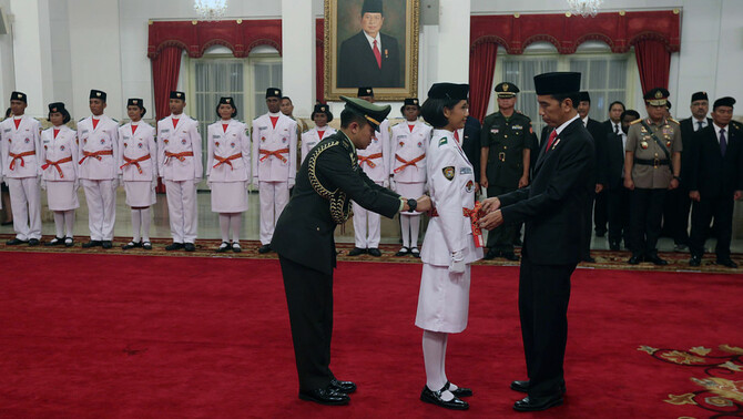 Presiden Joko Widodo (kanan) menyematkan kendit kepada Pemimpin upacara pengukuhan pasukan pengibar bendera pusaka (Paskibraka) 2017 Audrey Nathania Sumali (kiri) sebagai tanda pengukuhan anggota Paskibraka di Istana Negara, Jakarta, 15 Agustus 2017.