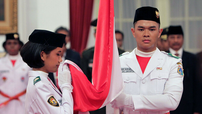 Pemimpin upacara pengukuhan pasukan pengibar bendera pusaka (Paskibraka) 2017 Audrey Nathania Sumali (kiri) mencium bendera merah putih dalam Pengukuhan Paskibraka 2017 di Istana Negara, Jakarta, 15 Agustus 2017.