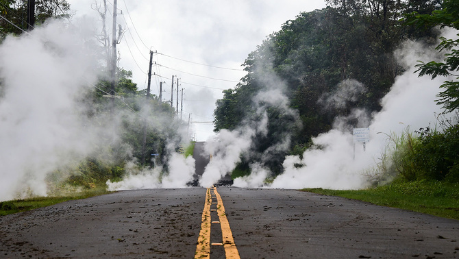 Asap putih mengepul dan keluar dari sela-sela retakan jalan dampak aktivitas vulkanik gunung Kilauea di Pulau Besar, Hawaii.