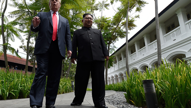 Pemimpin Korea Utara, Kim Jong Un (kanan) berjalan bersama Presiden Amerika Serikat, Donald Trump (kiri) di sela pertemuan bersejarah keduanya di halaman Hotel Capella, Singapura, 12 Juni 2018.