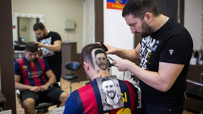 Penata rambut Serbia, Mario Hvala mencukur rambut bagian belakang seorang pelanggannya dengan gambar pesepakbola Timnas Argentina, Lionel Messi di Serbia, 10 Juni 2018.