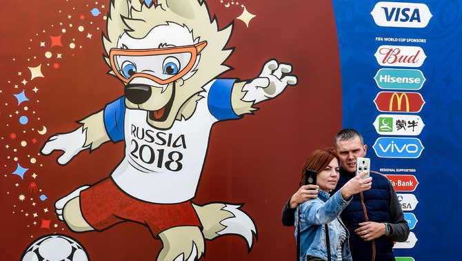 Dua warga berfoto di depan banner maskot resmi Piala Dunia 2018, Zabivaka di Saransk, Rusia, 11 Juni 2018.