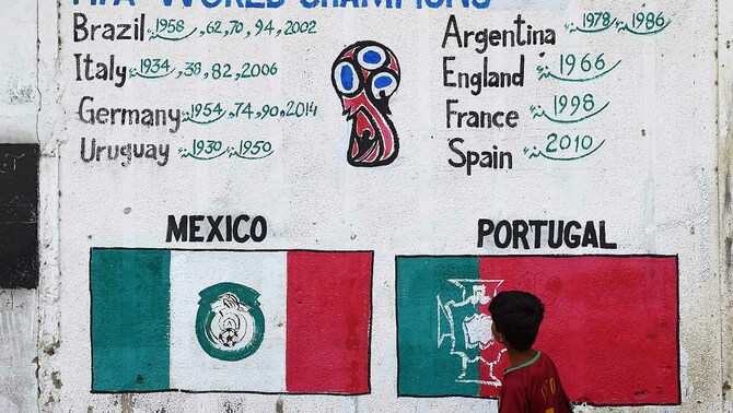 Seorang anak Pakistan melihat gambar bendera negara-negara peserta Piala Dunia 2018 yang dilukis di tembok di Lyari, Karachi, 13 Juni 2018.