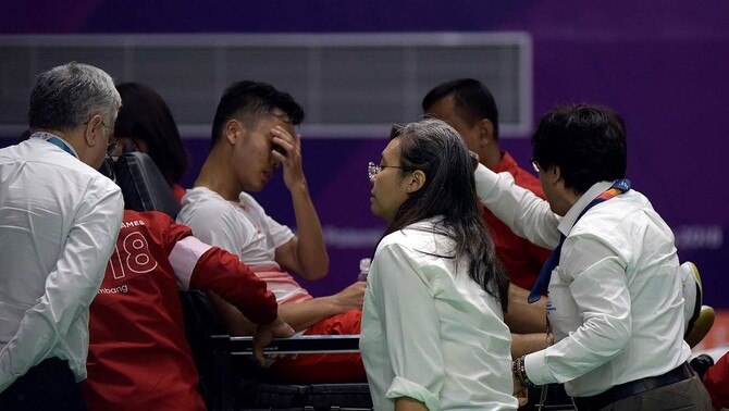 Pebulutangkis putra Indonesia Anthony Sinisuka Ginting (terbaring) ditandu keluar lapangan setelah mengalami cedera dalam pertandingan final beregu putra Asian Games 2018 melawan pebulutangkis putra Cina Shi Yuqi di Istora Senayan, Jakarta, 23 Agustus 2018.