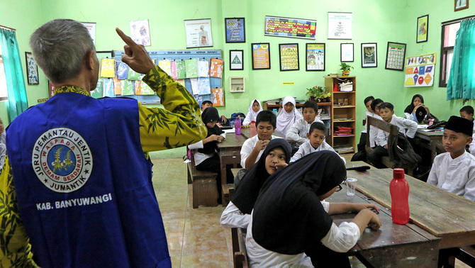 Tak hanya pengasapan, peyuluhan tentang Demam Berdarah Dengue (DBD) juga dilakukan hingga ke beberapa sekolah dan kantor instansi oleh petugas kesehatan. Petugas puskesmas memberikan penjelasan mengenai bahaya Demam Berdarah (DBD) kepada siswa Sekolah Dasar di Banyuwangi, Jawa Timur, 1 Februari 2019. Sosialisasi oleh Juru Pemantau Jentik (Jumantik) kepada masyarakat dan siswa tersebut sebagai upaya memberikan edukasi untuk mencegah penyebaran Demam Berdarah DBD. ANTARA FOTO/Budi Candra Setya/nz.