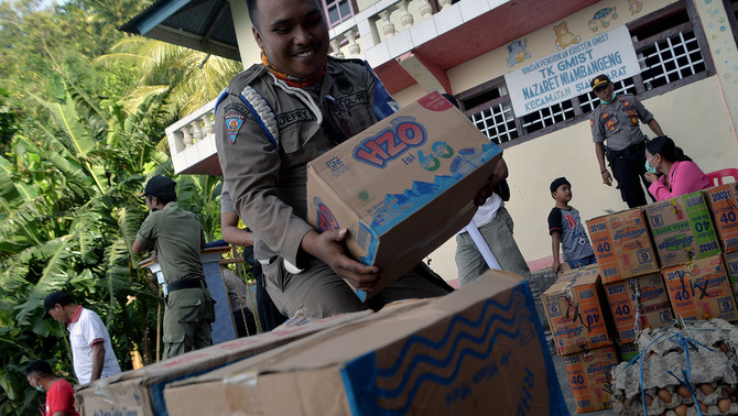 Anggota Satpol PP menumpuk pasokan logistik untuk warga di Desa Niambangeng, Siau Barat Utara, Kabupaten Kepulauan Sitaro, Sulawesi Utara, 6 Februari 2019. Pihak otoritas setempat mendistribusikan ratusan karton makanan instan, air mineral, telur, beras dan bahan makanan pokok lainnya melalui jalur darat dan diutamakan bagi warga desa terdampak erupsi Gunung Karangetang yang masih berada di penampungan sementara.