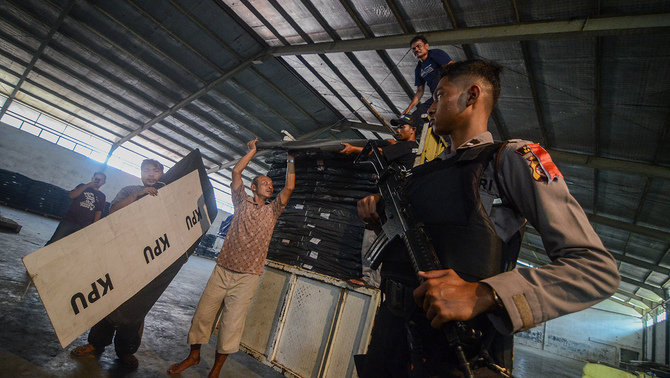 PENGAMANAN DISTRIBUSI LOGISTIK PEMILU - Pendistribusian logistik pemilu 2019 dikawal oleh petugas pengamanan dari TNI dan Polri hingga ke seluruh wilayah di Indonesia. Seorang anggota kepolisian berjaga saat petugas menurunkan logistik Pemilu dari truk di Gudang penyimpanan, Solokan Jeruk, Rancaekek, Kabupaten Bandung, Jawa Barat, 6 Februari 2019. KPU Kabupaten Bandung mendistribusikan ke gudang penyimpanan sebanyak 51.690 kotak suara, dan 41.352 bilik suara untuk keperluan Pemilu se-Kabupaten Bandung pada 17 April mendatang. ANTARA FOTO/Raisan Al Farisi/aww.