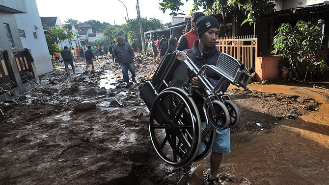 Seorang warga membawa kursi roda di komplek perumahan Jati Endah Regency, Pasir Jati, Cilengkrang, Kabupaten Bandung, Jawa Barat, pasca diterjang banjir bandang, 10 Februari 2019. Banjir bandang yang terjadi akibat jebolnya tanggul penahan air sungai saat hujan deras pada Sabtu (9/2) malam tersebut menyebabkan sekitar tujuh rumah rusak berat dan tiga orang tewas. ANTARA FOTO/Raisan Al Farisi/ama.