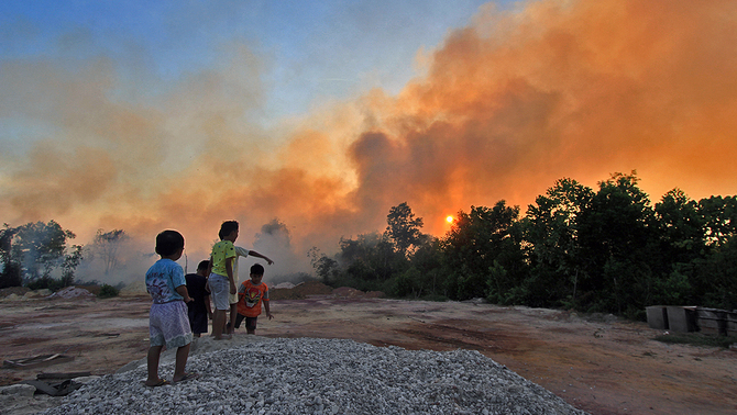 Sejumlah anak bermain di dekat pemukiman yang terdampak kebakaran hutan dan lahan, di kecamatan Dumai Barat kota Dumai, Dumai, Riau, 12 Februari 2019. Kebakaran hutan dan lahan yang terjadi di sejumlah daerah di pesisir Riau semakin meluas akibat cuaca panas. 