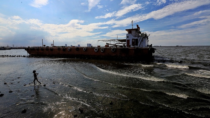 Seorang anak bermain di antara kapal yng bersandar di kawasan Dermaga Kali Adem, Muara Angke, Jakarta, Senin (13/1/2020).