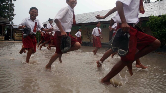 Sejumlah siswa SDN 29 Manggar, Desa Buku Limau, Belitung Timur,  melepas sepatu mereka saat  melintasi genangan air di sekolah mereka.  FOTO:  Yudhi Sukma Wijaya