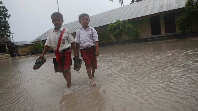Sejumlah siswa SDN 29 Manggar, Desa Buku Limau, Belitung Timur,  melepas sepatu mereka saat  melintasi genangan air di sekolah mereka.  FOTO:  Yudhi Sukma Wijaya