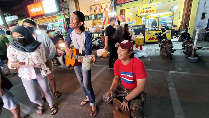 Pengamen di Tangerang, Banten, Jumat, 25 Februari 2022. Berbagai jajanan dijual, di Jalan yang ditetepakan  menjadi kawasan Culinary Night Kota Tangerang  pada 2014 silam itu seperti tak mengenal pemberlakuan pembatasan aktivitas manusia terkait penyebaran virus Corona. 