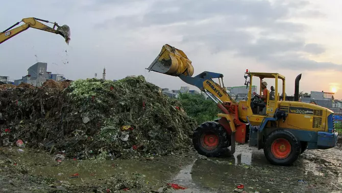 Petugas menggunakan alat berat merapikan tumpukan sampah di Tempat Pembuangan Sementara (TPS) Pasar Induk Kramat Jati, Jakarta, Rabu 8 April 2026.