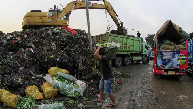 Petugas menggunakan alat berat mengangkut tumpukan sampah ke dalam truk, di Tempat Pembuangan Sementara (TPS) Pasar Induk Kramat Jati, Jakarta, Rabu 8 April 2026.