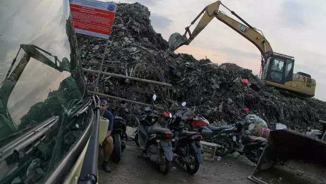 Petugas menggunakan alat berat merapikan tumpukan sampah di Tempat Pembuangan Sementara (TPS) Pasar Induk Kramat Jati, Jakarta, Rabu 8 April 2026.