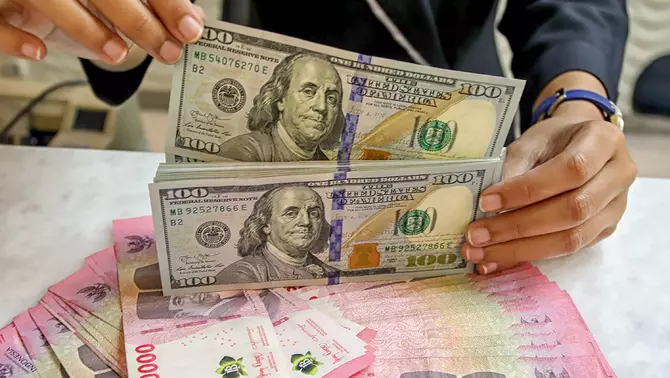 Petugas kasir menunjukkan uang pecahan dolar Amerika Serikat (AS) di gerai penukaran mata uang asing Ayu Masagung, Jakarta Pusat, Selasa 12 Mei 2026.