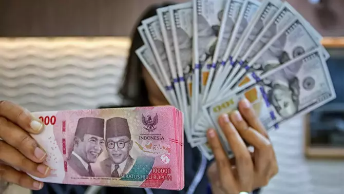 Petugas kasir menunjukkan uang pecahan dolar Amerika Serikat (AS) di gerai penukaran mata uang asing Ayu Masagung, Jakarta Pusat, Selasa 12 Mei 2026.