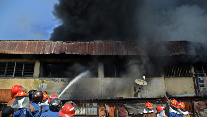 Petugas pemadam kebakaran berupaya memadamkan api yang membakar kompleks rumah toko di kawasan Pasar Kanjengan Semarang, Jateng, 18 Juni 2016. Penyebab kebakaran yang melanda belasan ruko tersebut diduga berasal dari hubungan pendek pendek listrik. Antara/R. Rekotomo