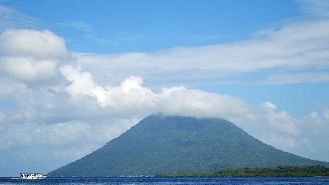 Sebuah kapal wisatawan melintas di perairan Taman Nasional Laut Bunaken dengn latar belakang Gunung Manado Tua, Manado, Sulawesi Utara, 31 Maret 2016. FOTO: BeritaSatu Photo/Danung Arifin